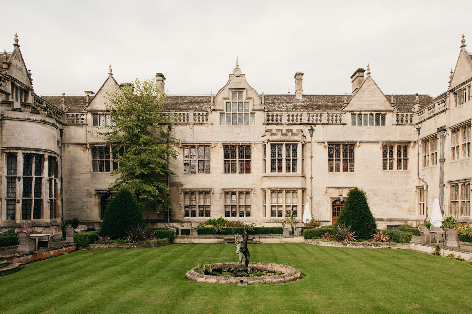 Historic stone manor house with Tudor architecture and manicured lawn.