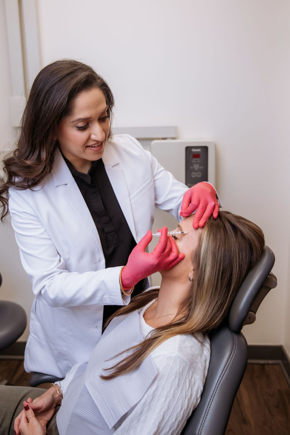 Dental provider wearing white coat performing botox injection on patient in clinical setting.