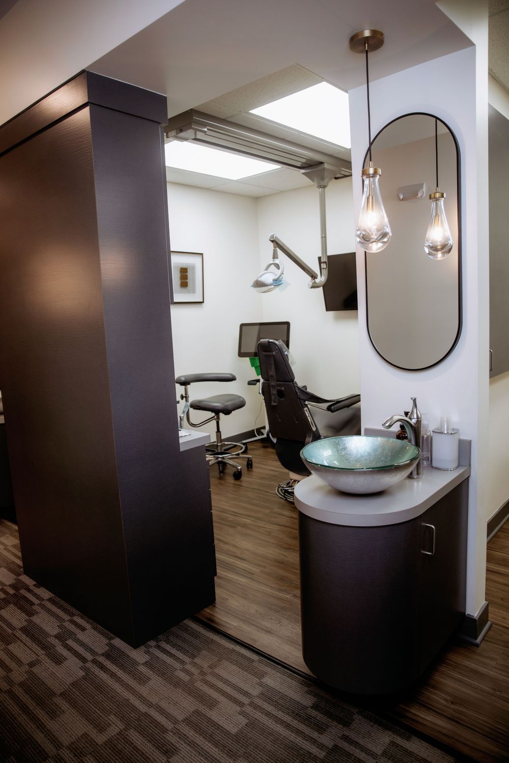 Modern dental treatment room with ergonomic chair, pendant lighting, and sleek fixtures.