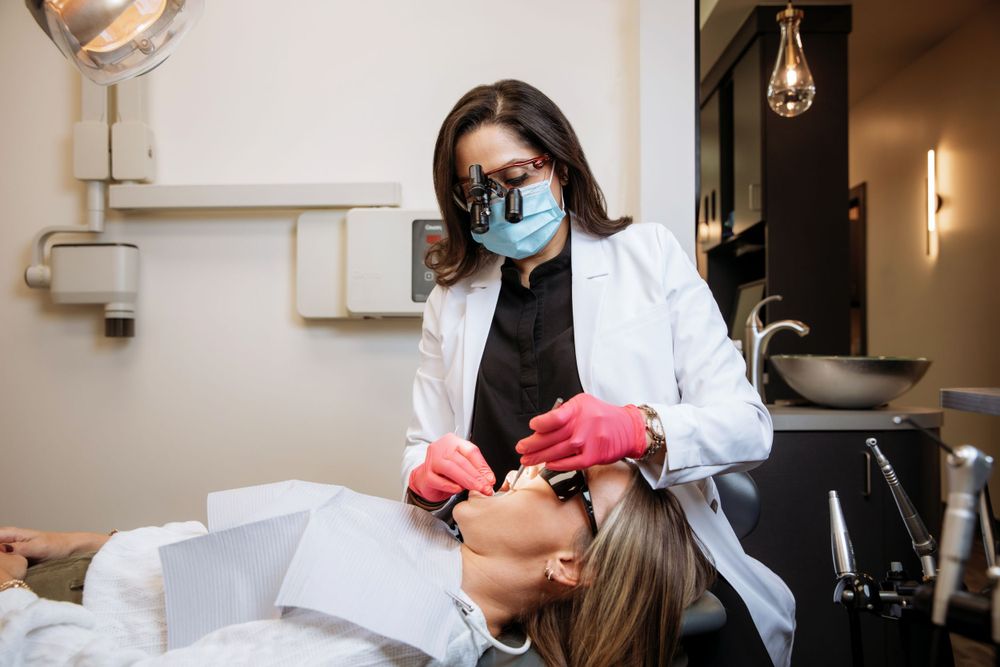 Dental professional wearing protective mask while treating patient during procedure.