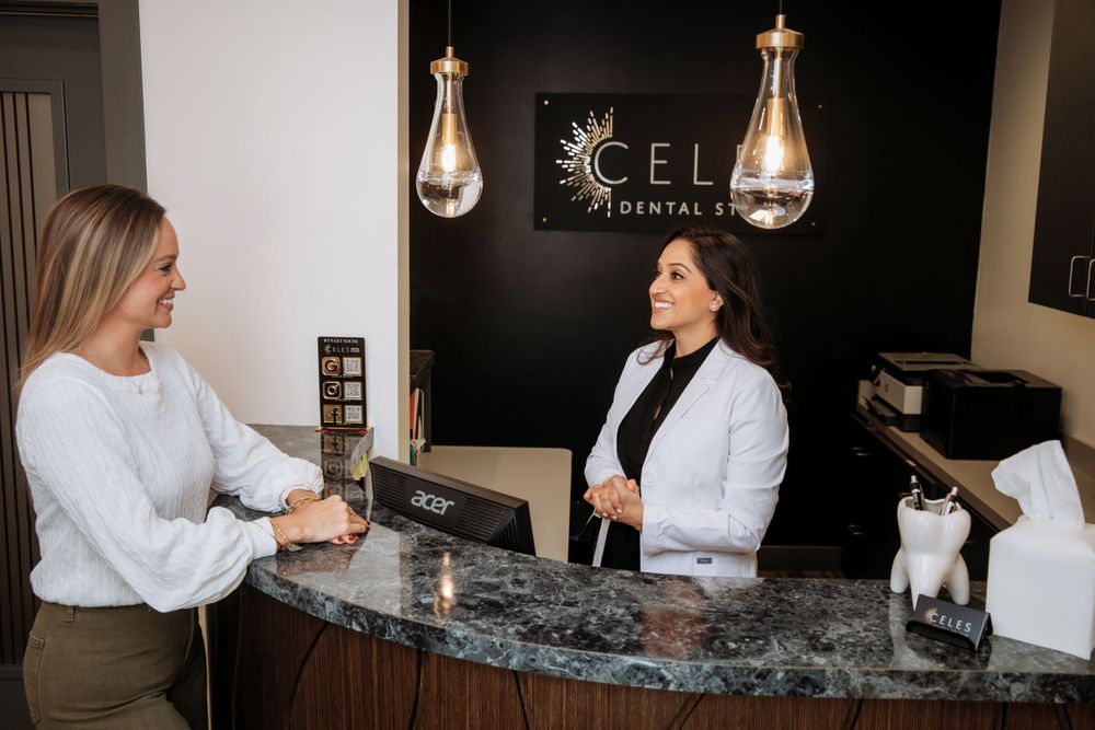Staff members having conversation at modern dental office reception desk with marble countertop.