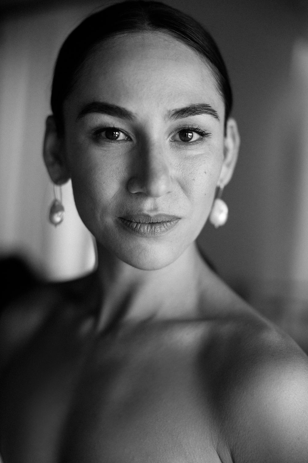 Close-up portrait of a person wearing pearl drop earrings in dramatic black and white lighting. Skopelos island, Greece