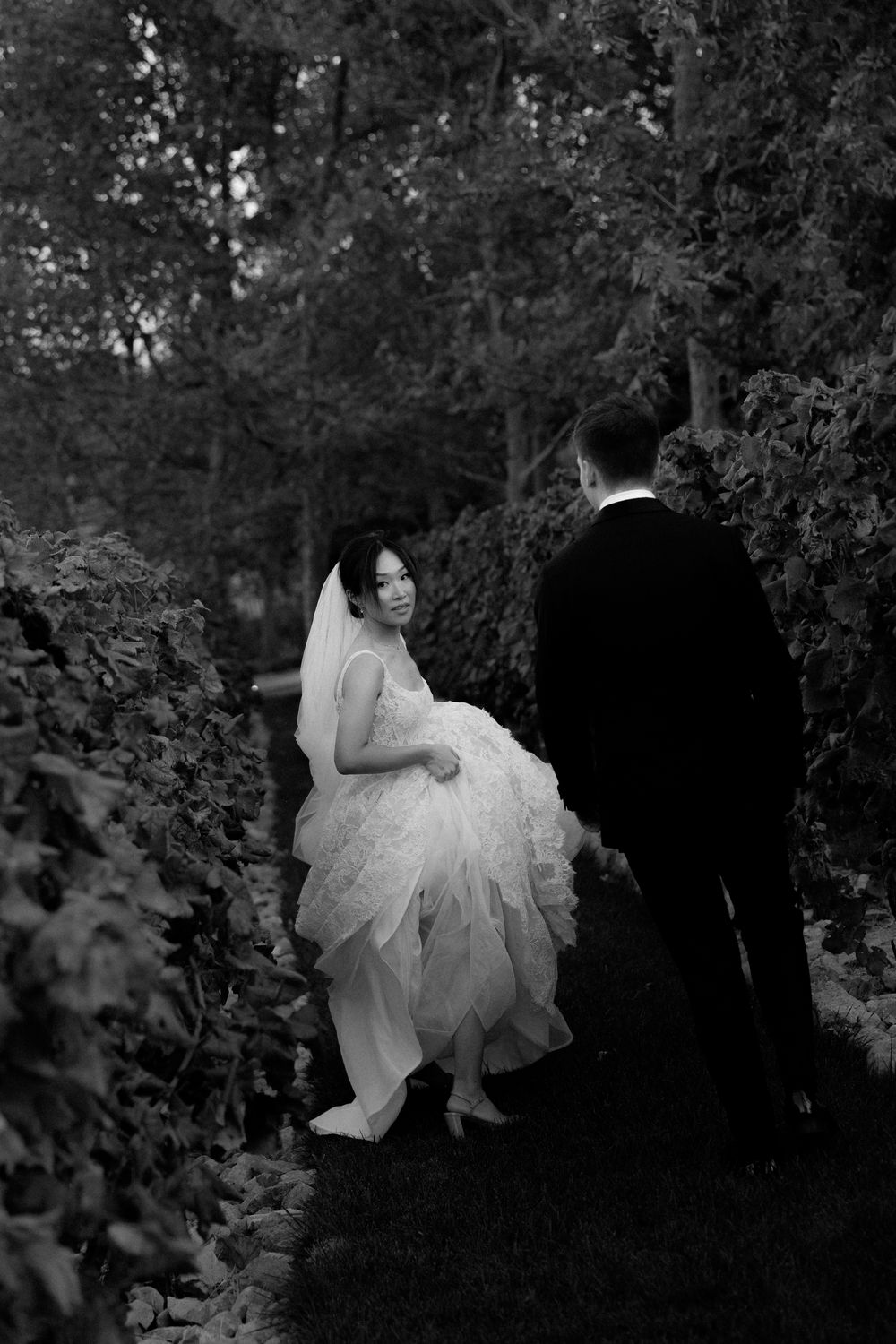 Wedding couple shares intimate moment on garden path surrounded by lush foliage. Pyrgos Petreza, Athens.