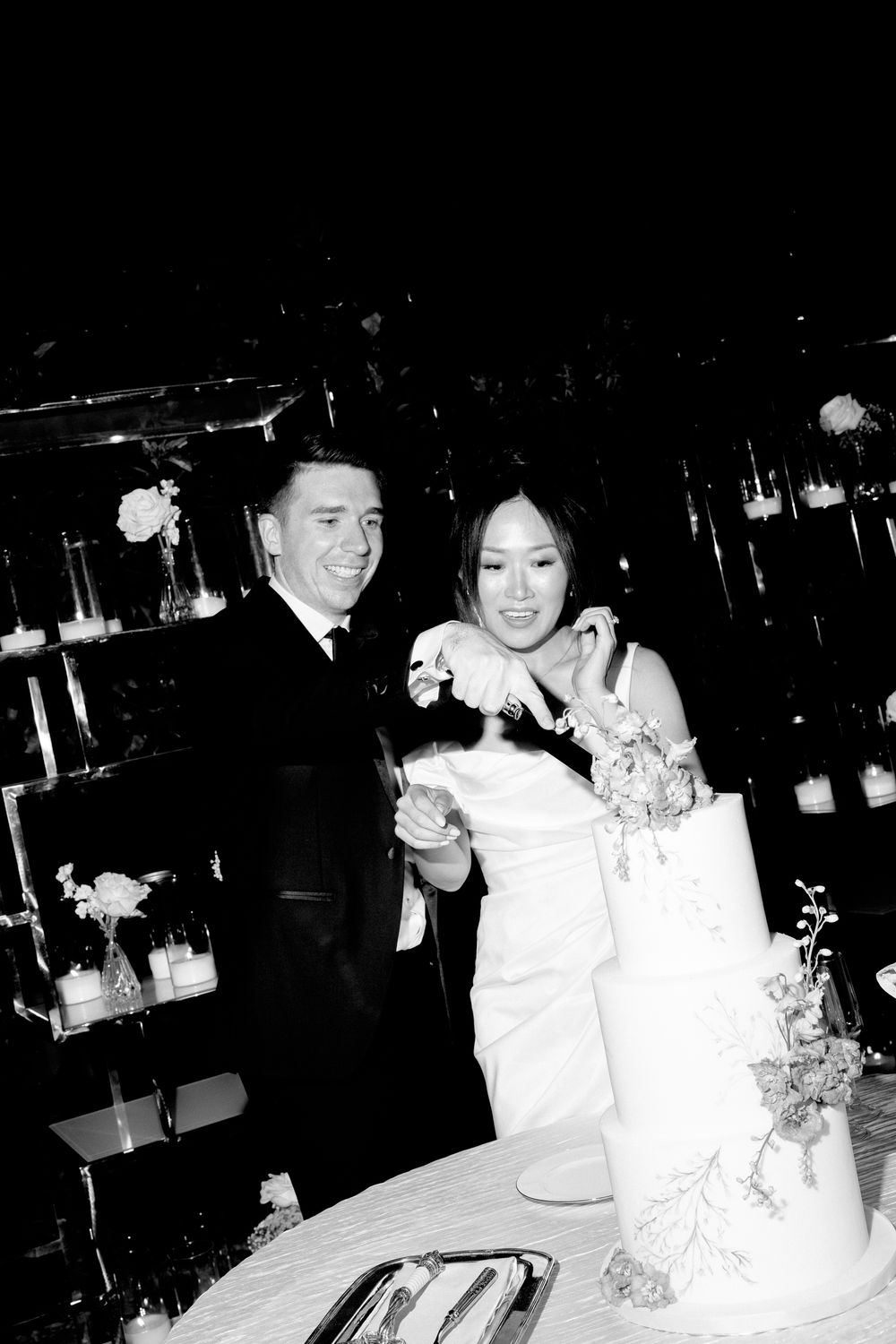 A black and white photo of newlyweds cutting their wedding cake together during their reception celebration at Pyrgos Petreza, Athens.