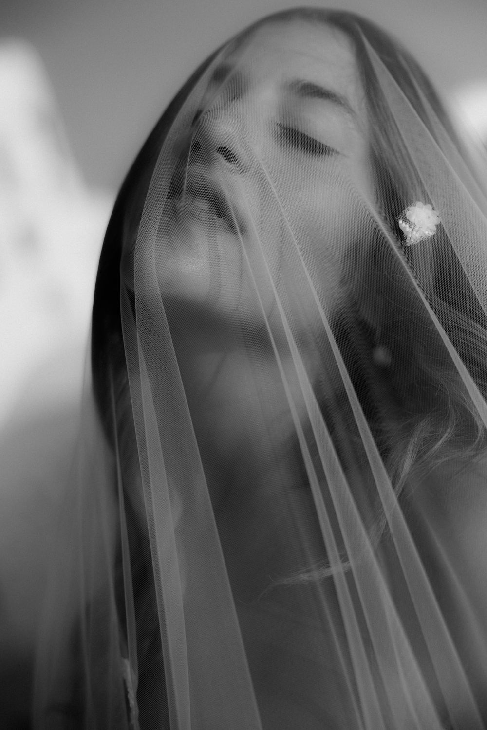 An artistic black and white portrait of a bride wearing a delicate veil. Astypalaia island, 2024.