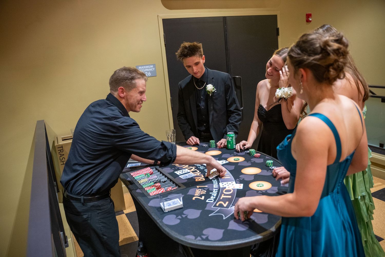 Players gathered around a poker table during what appears to be a formal event with fancy attire.