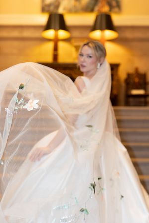 Ethereal bridal portrait with flowing veil and delicate floral embellishments in warm ambient lighting.