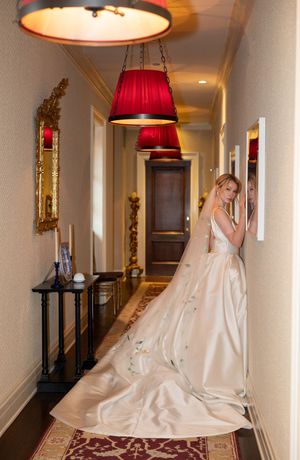 Dramatic hallway with red pendant lights showcasing bride in flowing silk wedding dress.