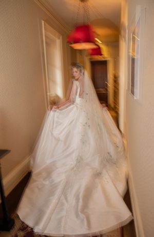 Bride in a flowing white gown twirling in a hallway with red pendant lights.