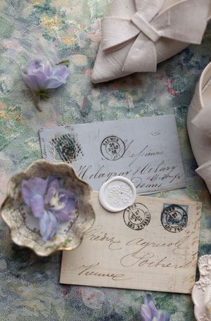 Vintage love letters with wax seals and purple flowers arranged on a textured background.
