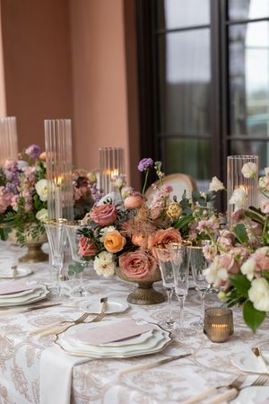 Elegant wedding table setting with pink and peach roses and crystal glassware.