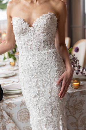 Close-up of a white lace wedding dress bodice with intricate floral appliques and sweetheart neckline.