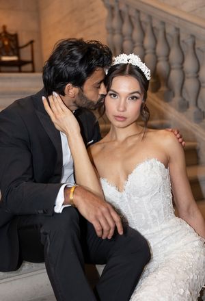 A romantic wedding couple share an intimate moment while seated on marble stairs.
