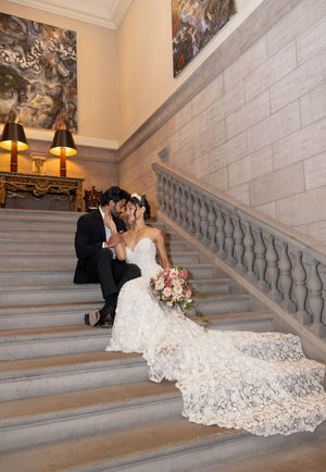 A romantic wedding moment on grand marble stairs with a flowing lace train.