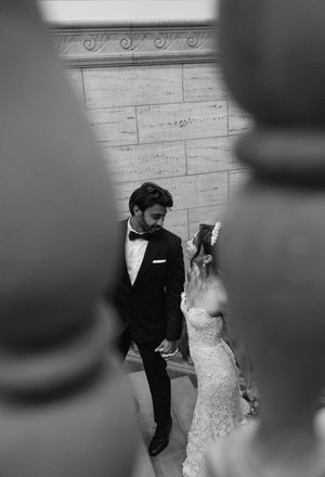 Black and white artistic wedding photo capturing a dramatic moment against ornate wall architecture.