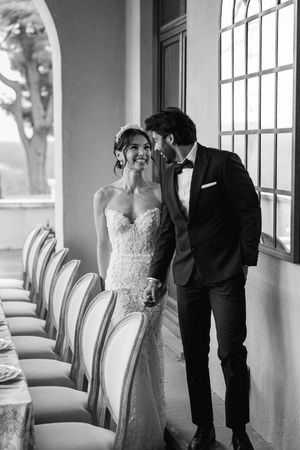 Intimate black and white portrait of couple sharing romantic moment by sunlit window.