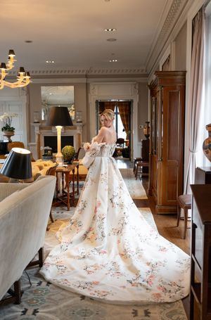 Wedding gown with floral embroidered train displayed in luxurious hotel setting.