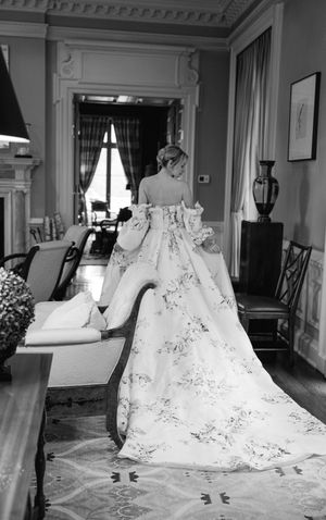 Back view of an ornate floral wedding dress with long train in an elegant room with classic decor.