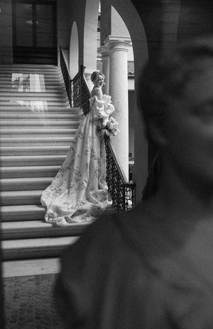 Dramatic black and white photo of wedding dress silhouette against architectural staircase.