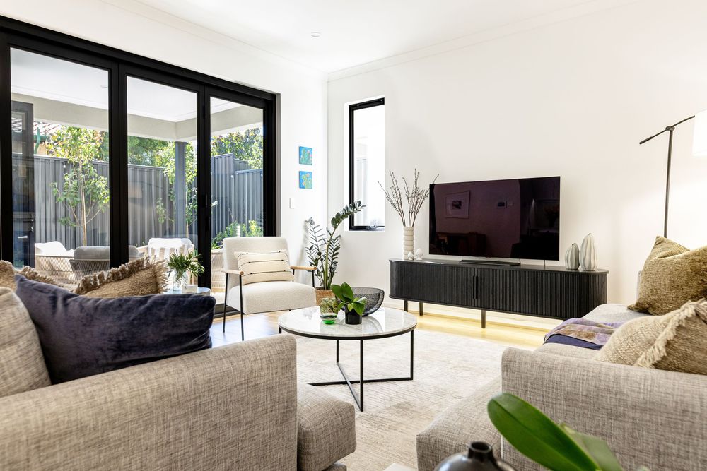 Modern living area with floor-to-ceiling windows, beige sofas, round coffee table and a tv for relaxing.