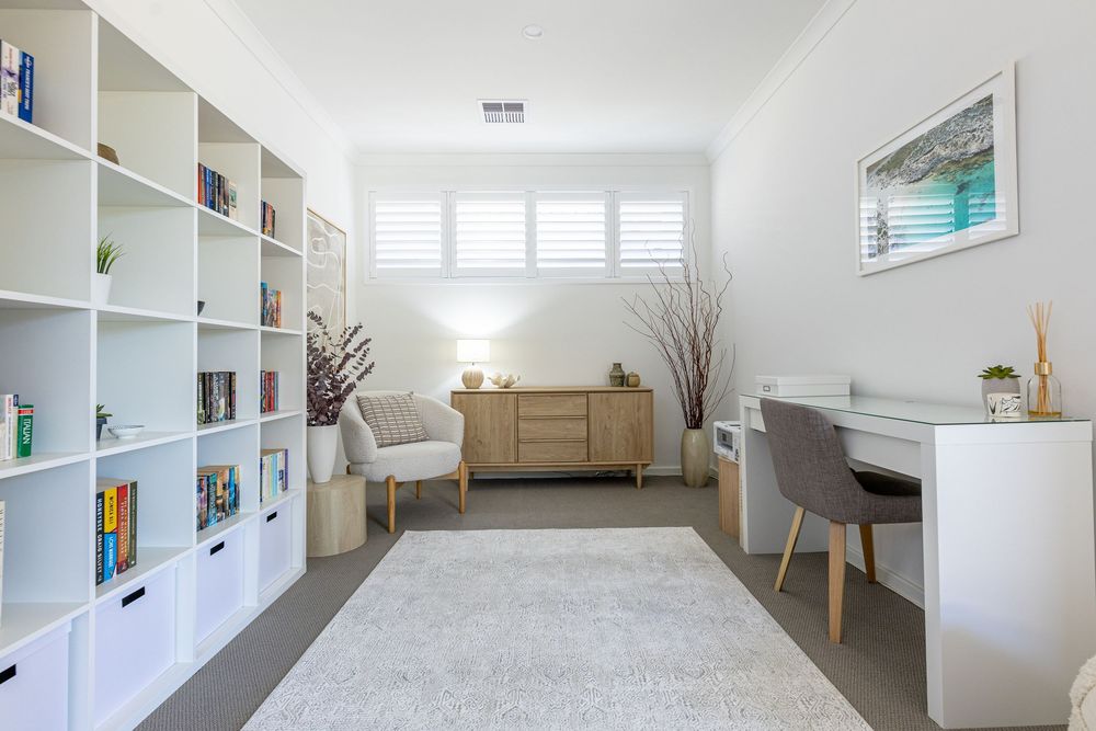 Photographer Kirsten Graham captures a home office space with built-in shelving, desk area, and comfortable seating on a plush grey carpet.