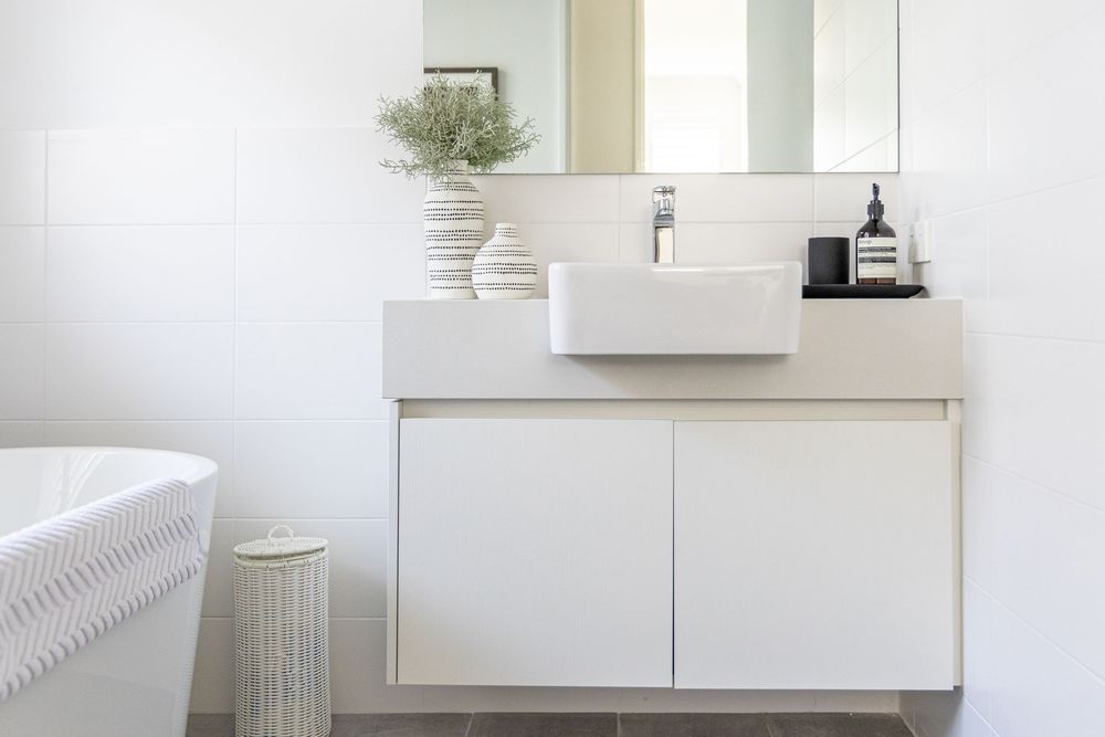 Modern white bathroom vanity with floating cabinet, vessel sink, and minimalist decor on a tiered countertop. Perth Commercial Photographer
