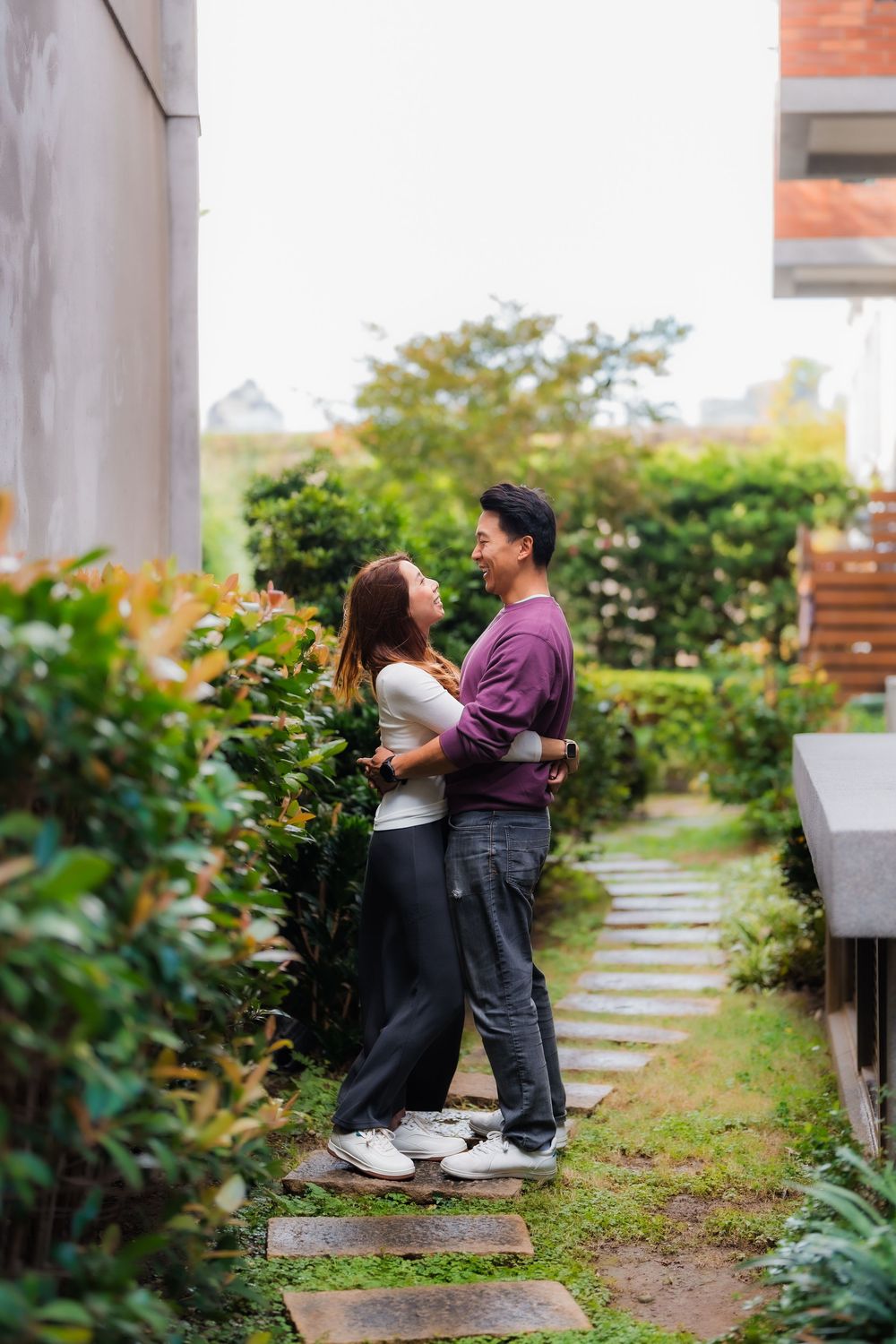 A couple hugging in a lush garden pathway with stepping stones and greenery at Dihua Street in Dadaocheng, Datong District, Taipei.