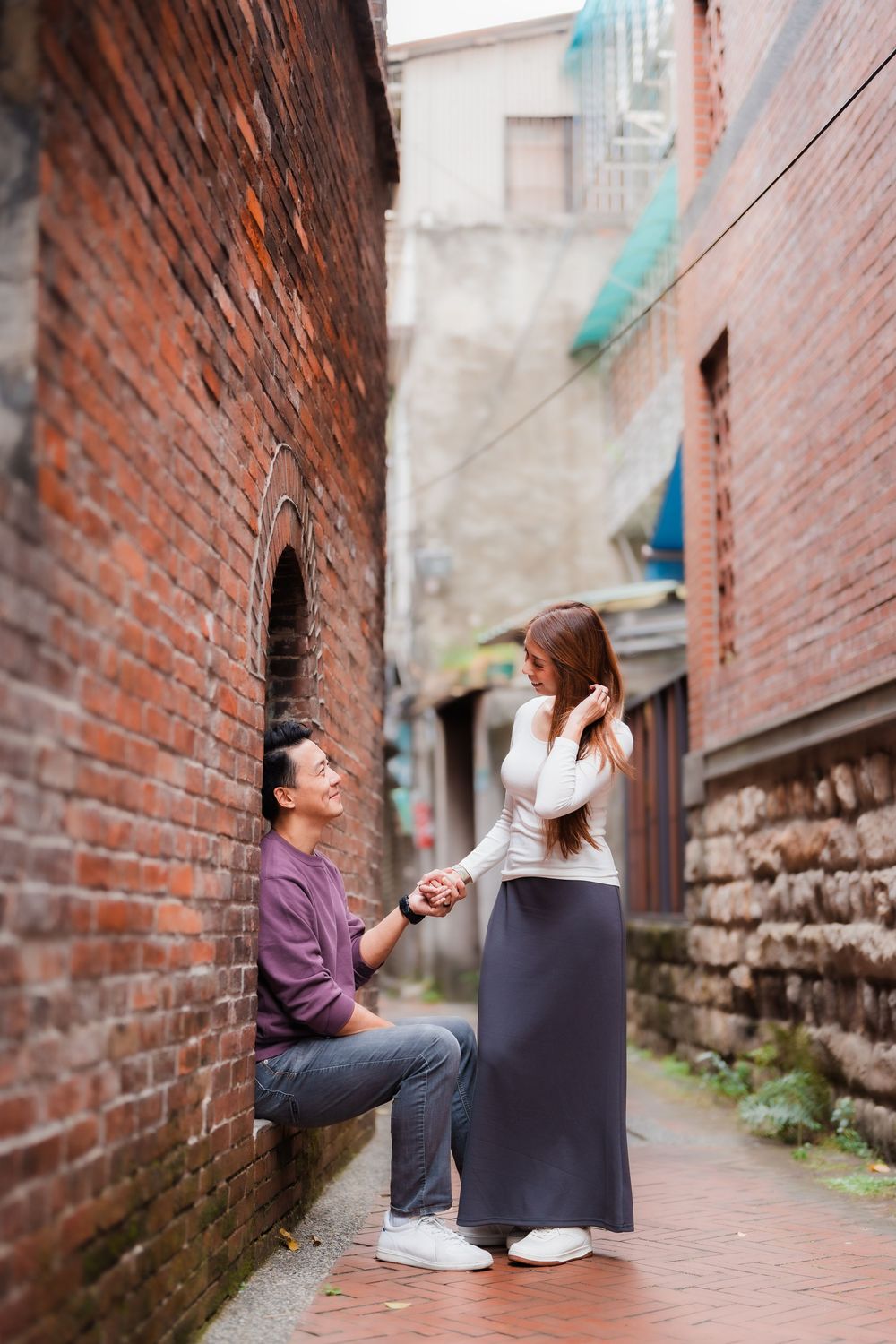 A couple sharing a romantic moment in a brick alleyway in Dadaocheng, Datong District, Taipei.