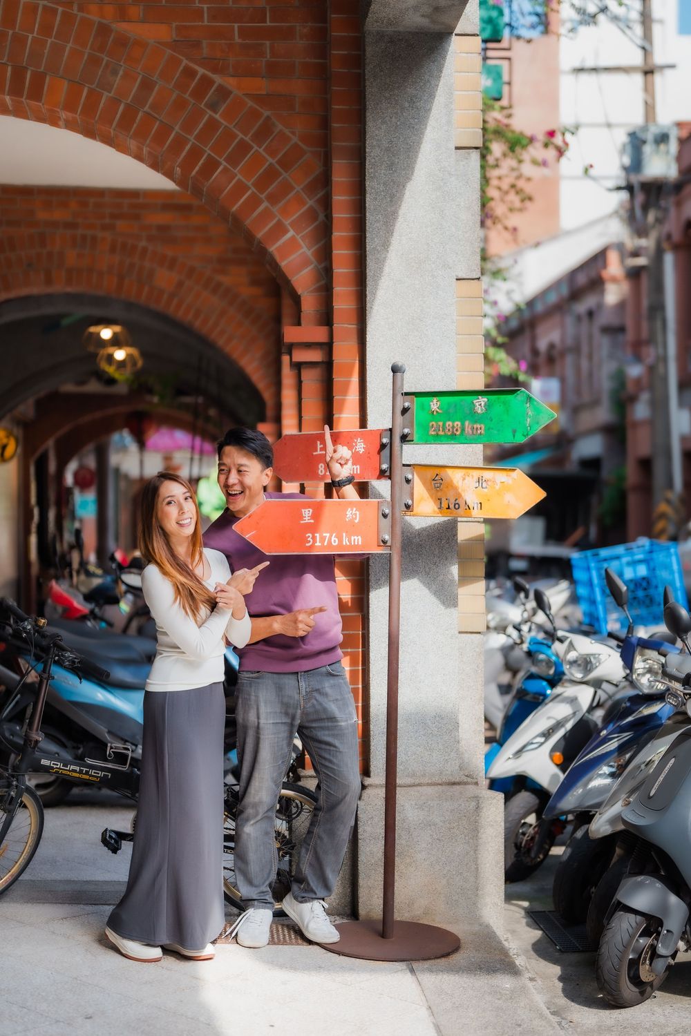 A couple standing by colorful directional signs on Dihua Street in Dadaocheng, Datong District, Taipei.