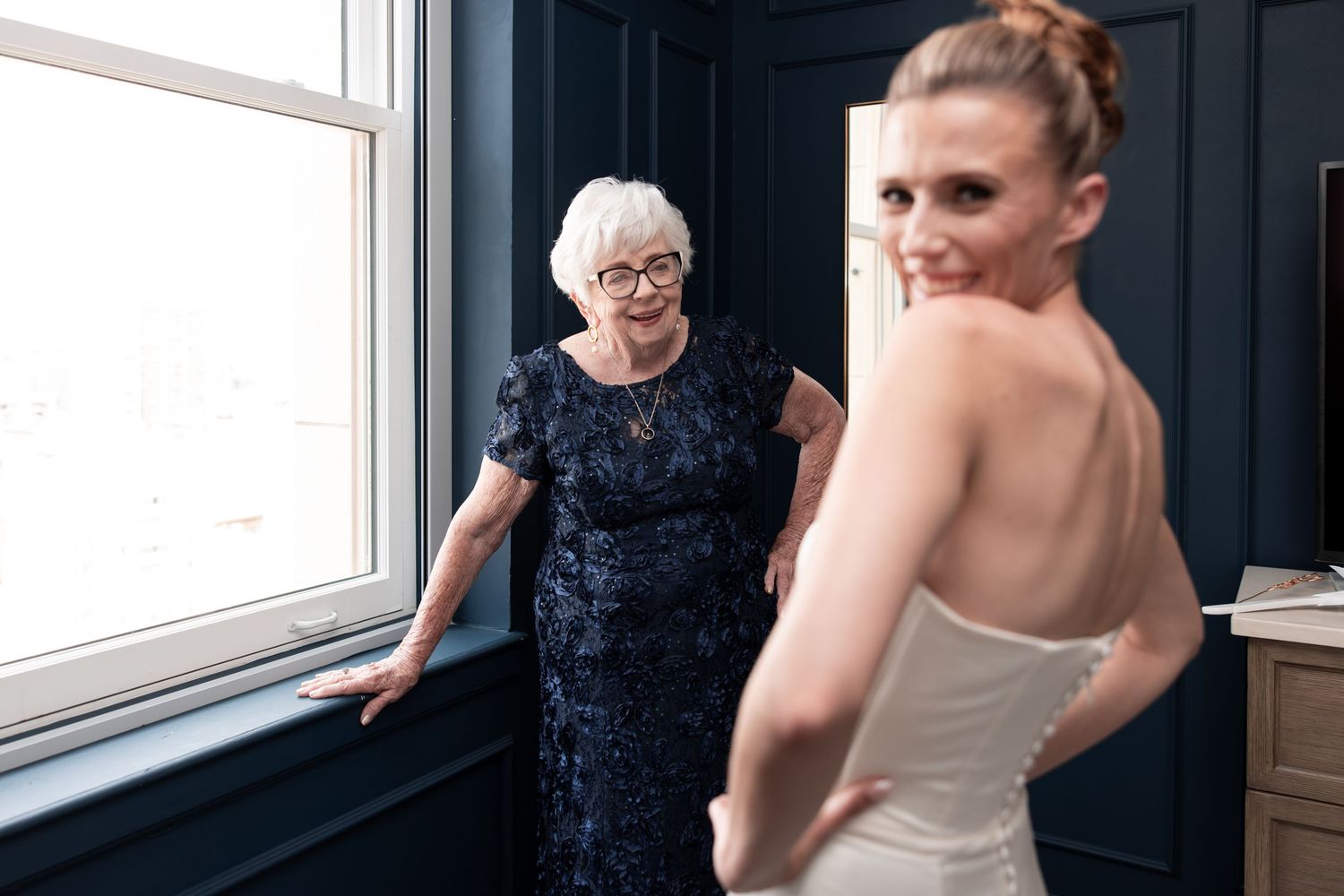 Bride in white gown and veil at elegant staircase wedding ceremony with floral arrangements and officiant.