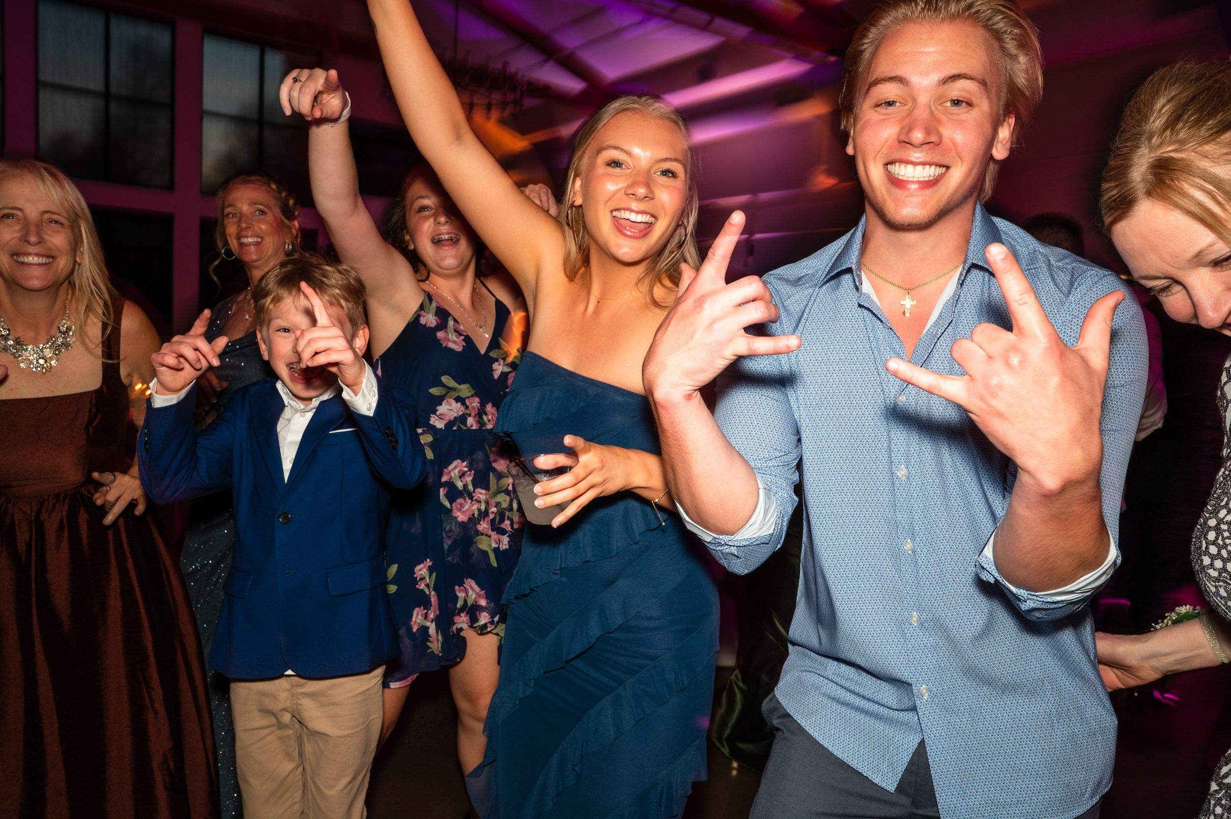 Guests dancing and celebrating at a lively wedding reception party with colorful lighting.