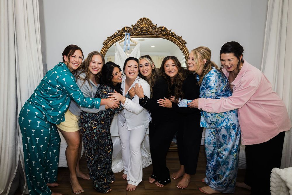 Bride celebrates with bridesmaids in colorful pajamas during a fun wedding morning getting-ready party.