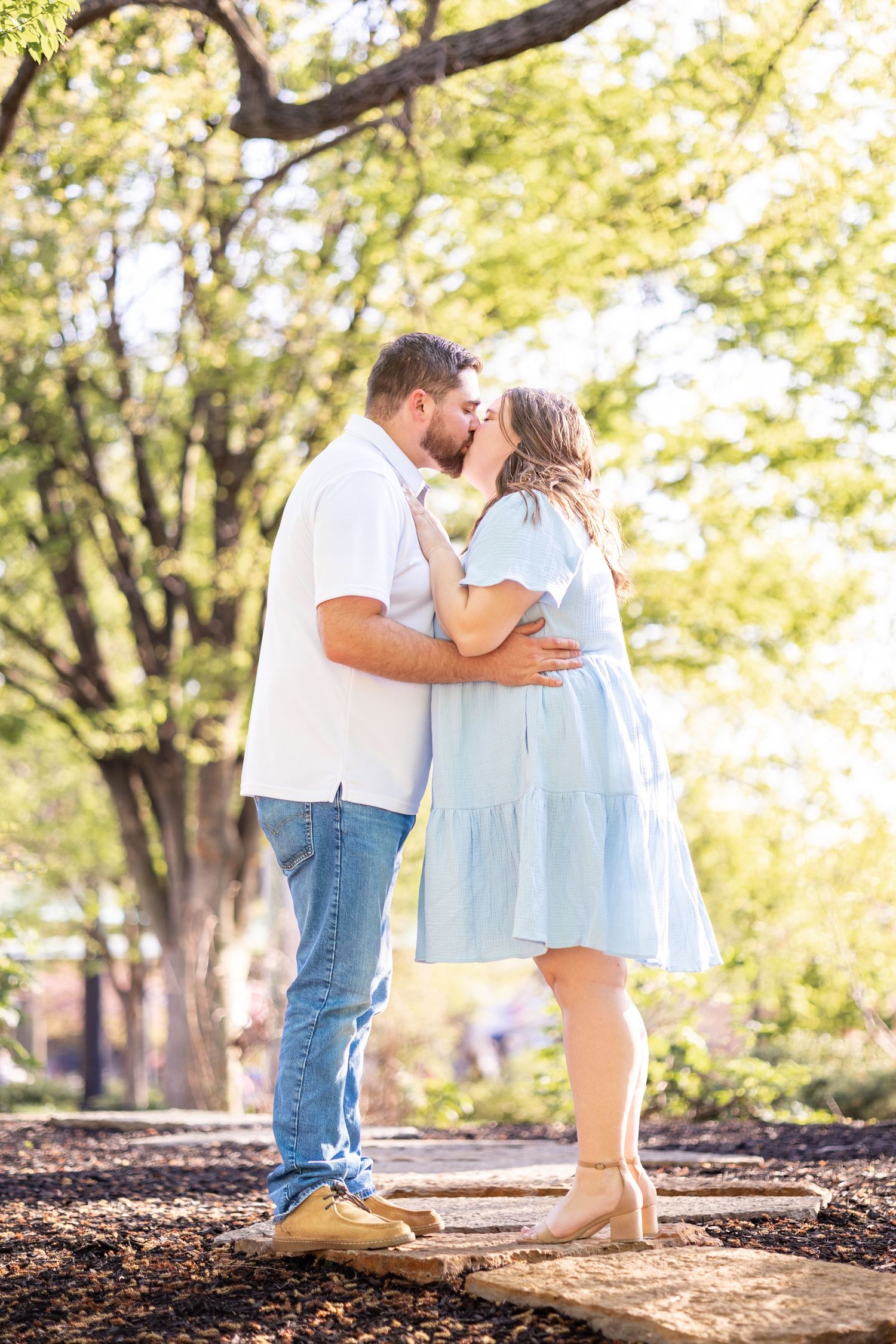 Couple sharing a romantic kiss outdoors in a sunny park at washington, a top Cincinnati proposal location
