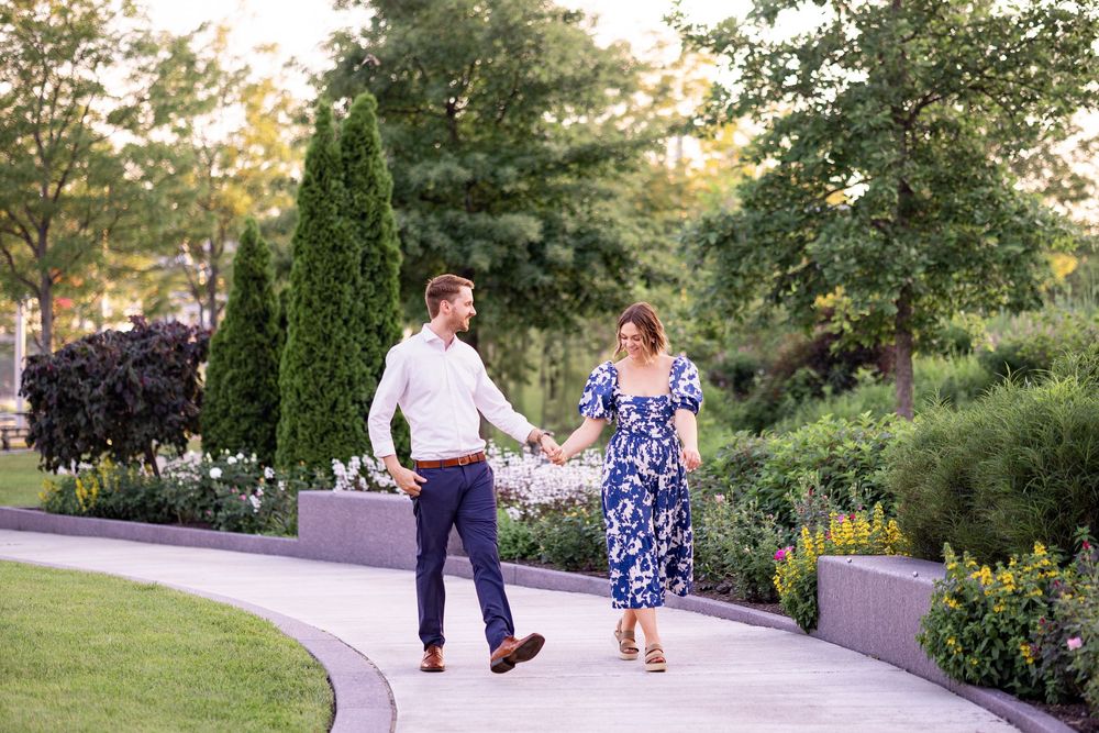 Couple holding hands walking on garden path, woman in blue floral dress. Rose Garden in Smale Park, Cincinnati Ohio.