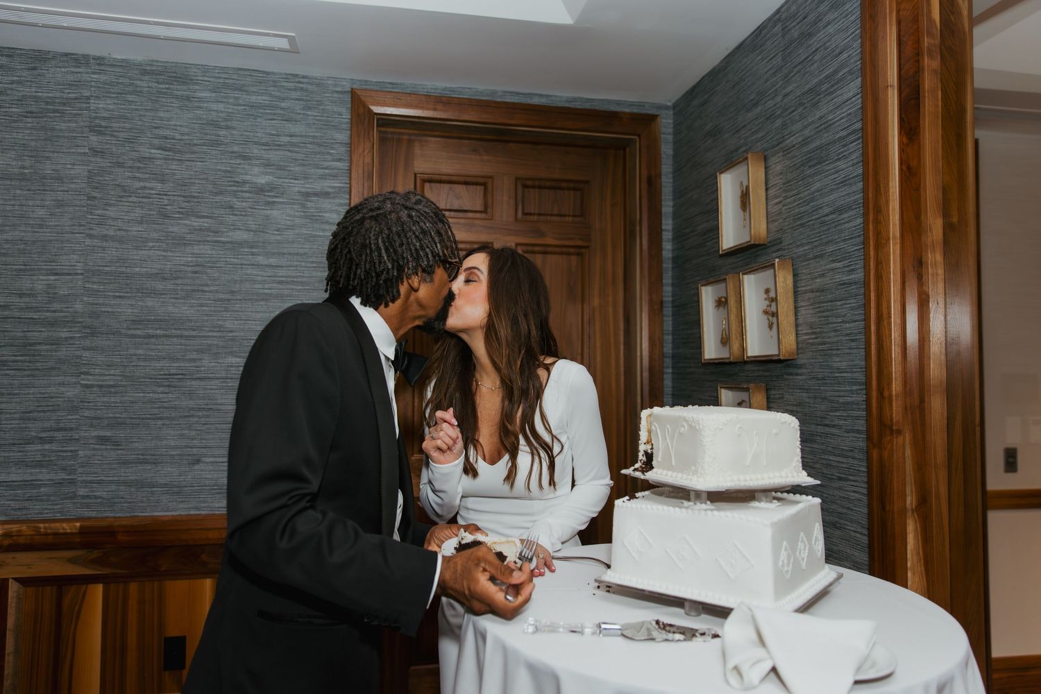 Bride and groom share a kiss after cutting their cake at their wedding reception at holliday Farms in Zionsville, Indiana
