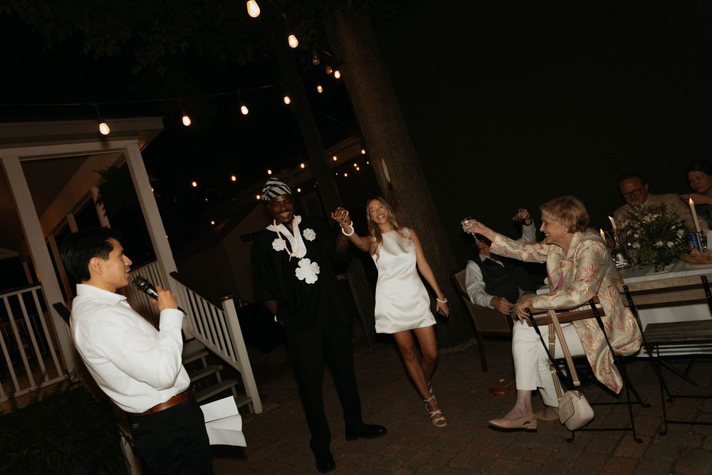 Bride and groom dancing outdoors at night under string lights during their wedding reception.