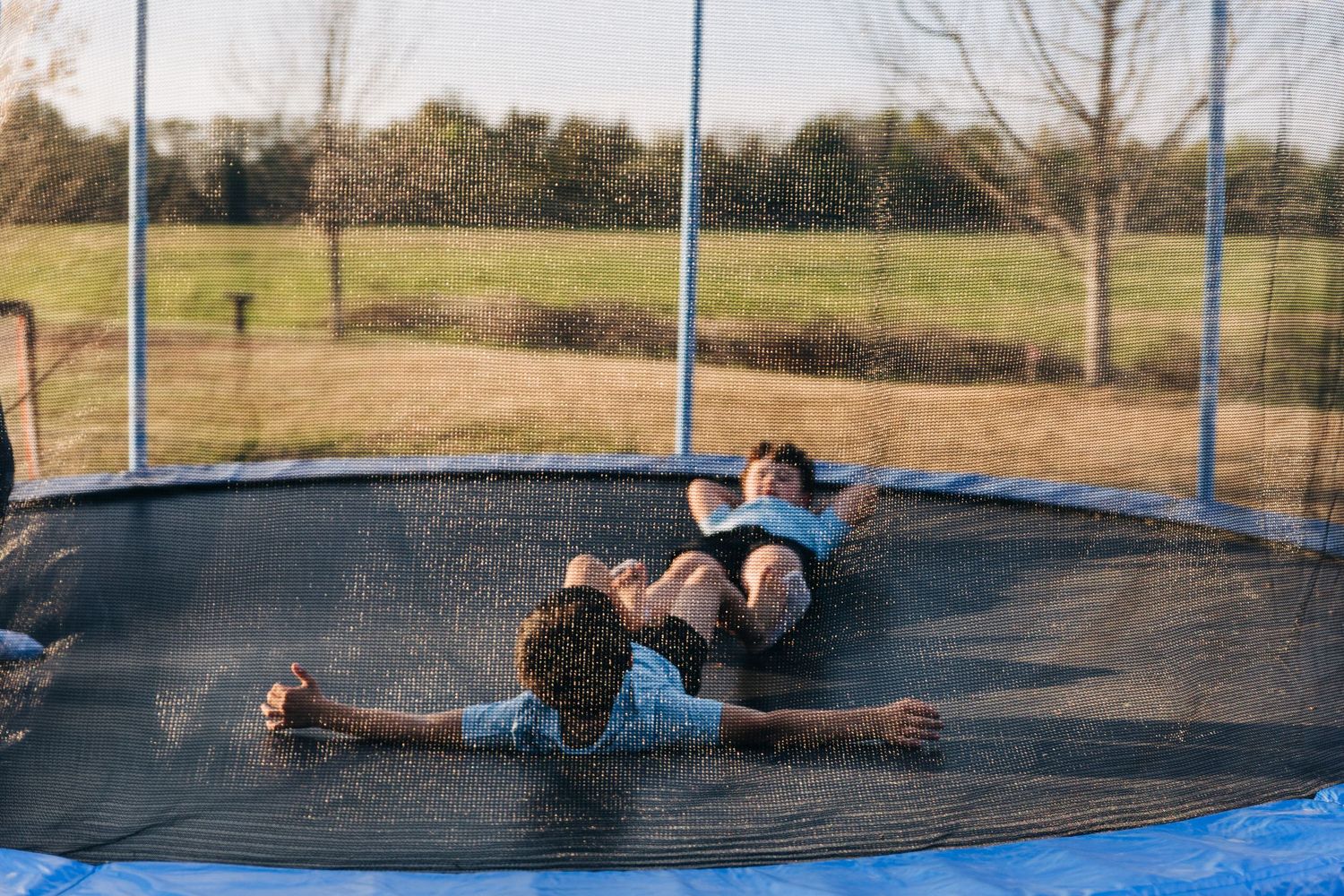 Two brothers lay on a trampoline and look at each other.