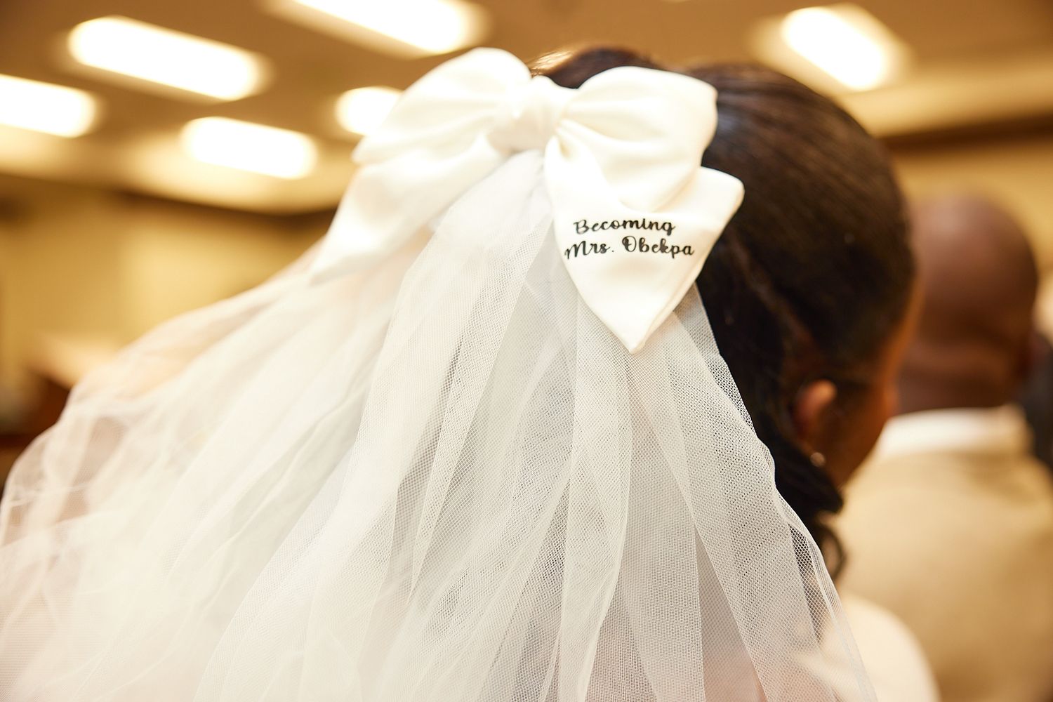 Close-up of a bridal veil hair bow reading Becoming Mrs. Phillips on a Black bride's hair.