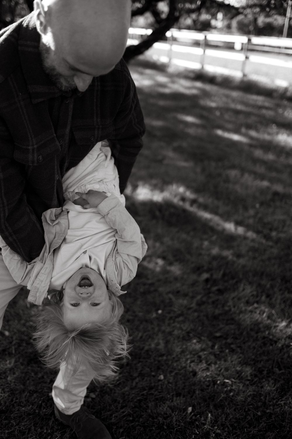 father holding his son upside down in outdoor family photoshoot while being captured by storytelling family photographer in Stockholm