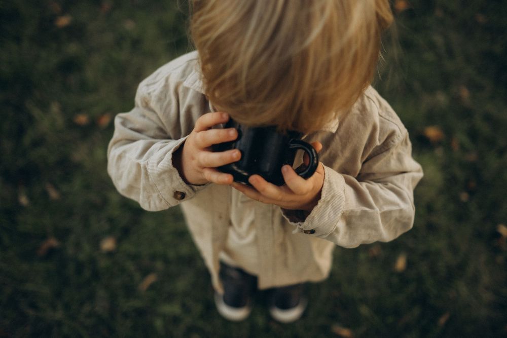 little boy drinking from a cup with his whole head buried in it while being captured by documentary family photographer in Stockholm