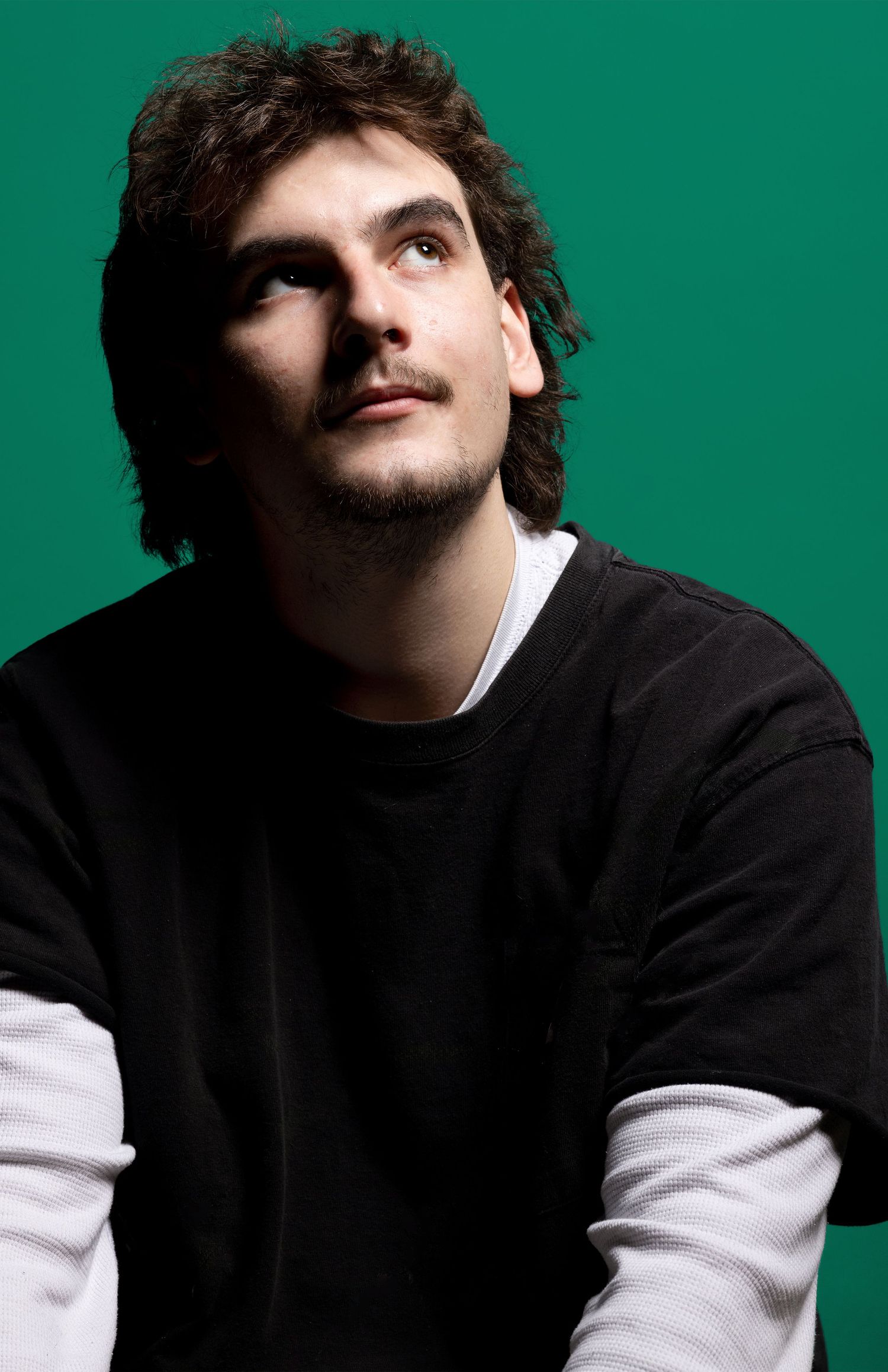 Studio portrait of a person looking upward against a green background.