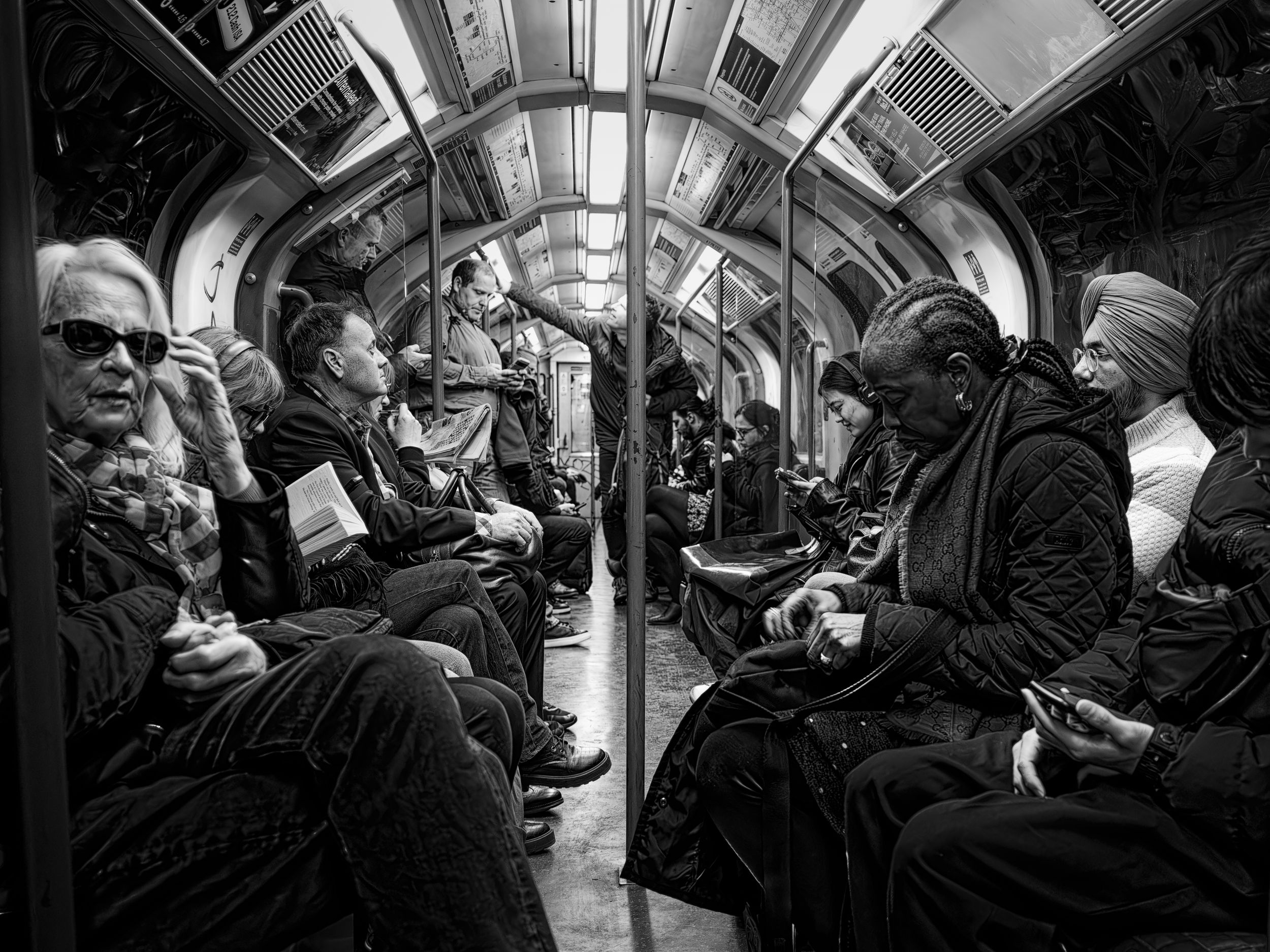 Black and white street photography of passengers seated inside a subway train carriage