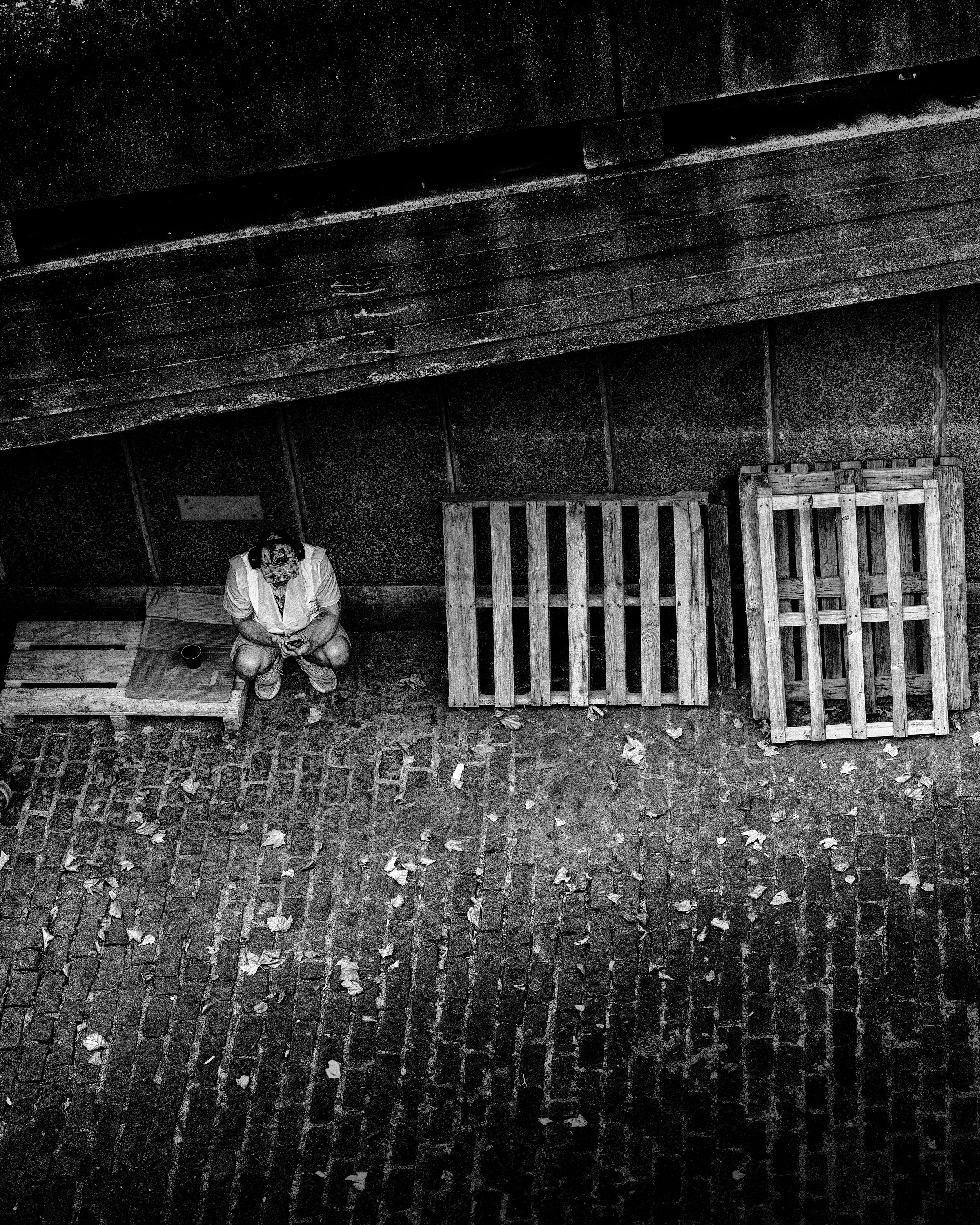 Black and white street photography of two people sitting on a bench near an old building