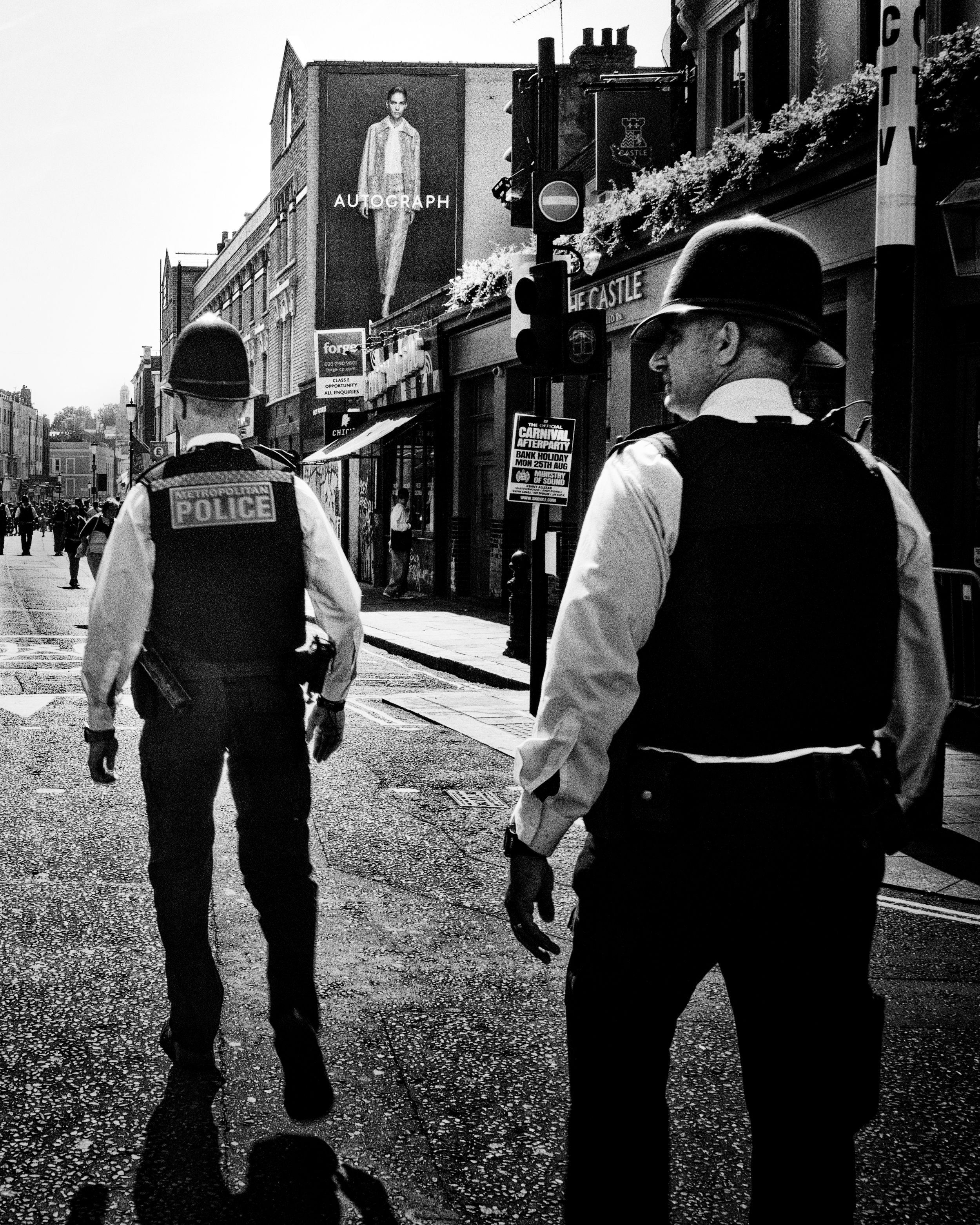 Black and white street photography of two police officers walking on a city street