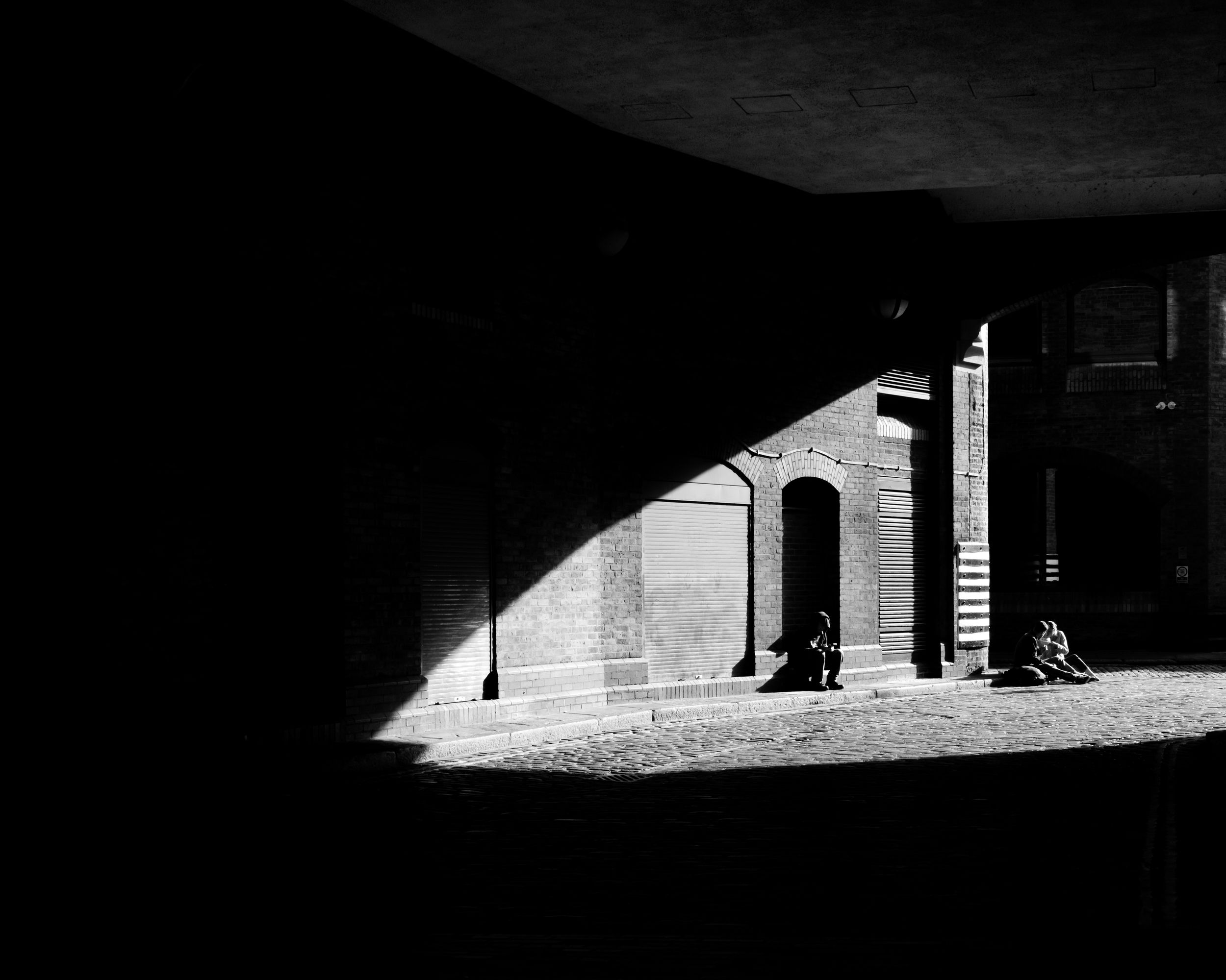 Dramatic black and white architectural photo of light streaming through a dark archway