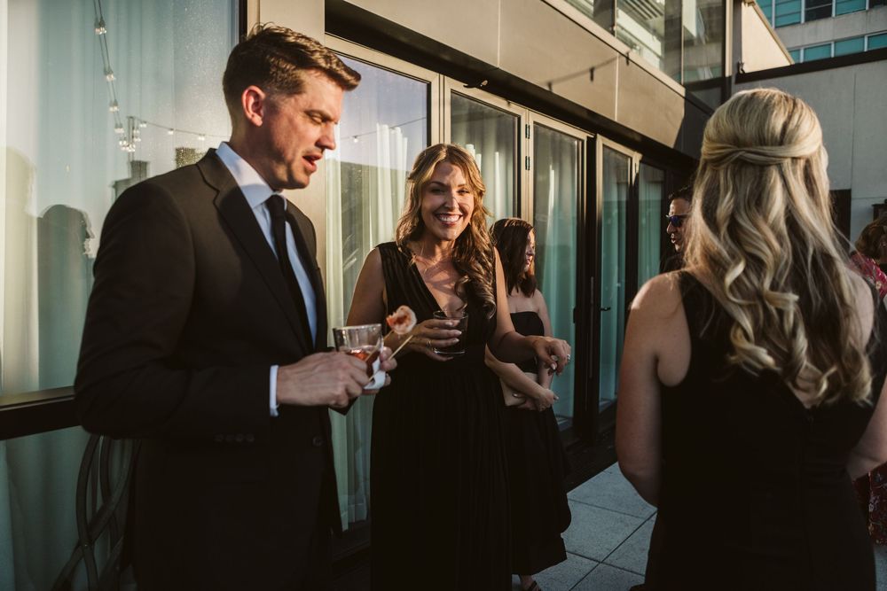 Elegantly dressed guests socializing at an upscale evening event on a modern outdoor terrace.