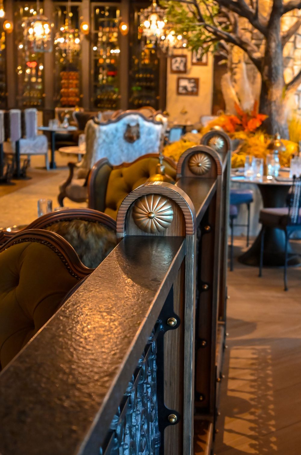 Elegant restaurant interior with ornate metal railing, tufted leather chairs, warm lighting, and floral arrangements.