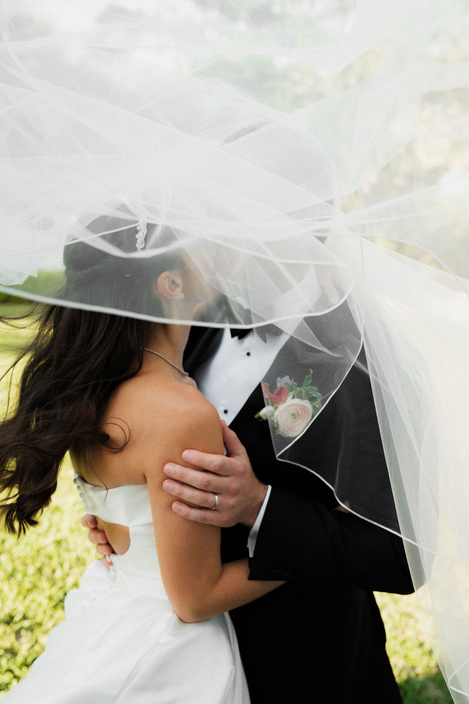 Bride and groom share a romantic kiss in elegant venue with warm pendant lights and classic black-and-white checkered floor.
