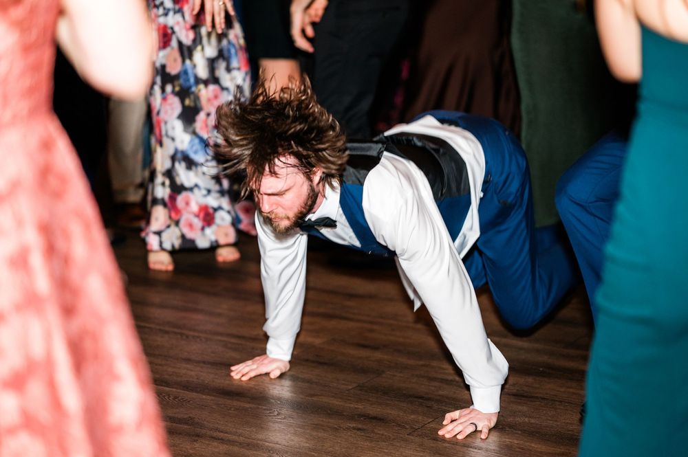 Groom doing push-ups on the dance floor at a lively wedding reception.
