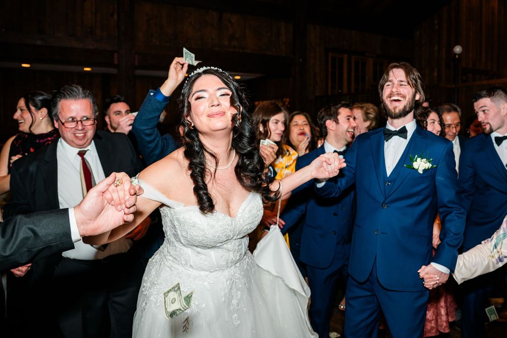 Joyful bride in white gown dancing with groom in blue suit at lively wedding reception.